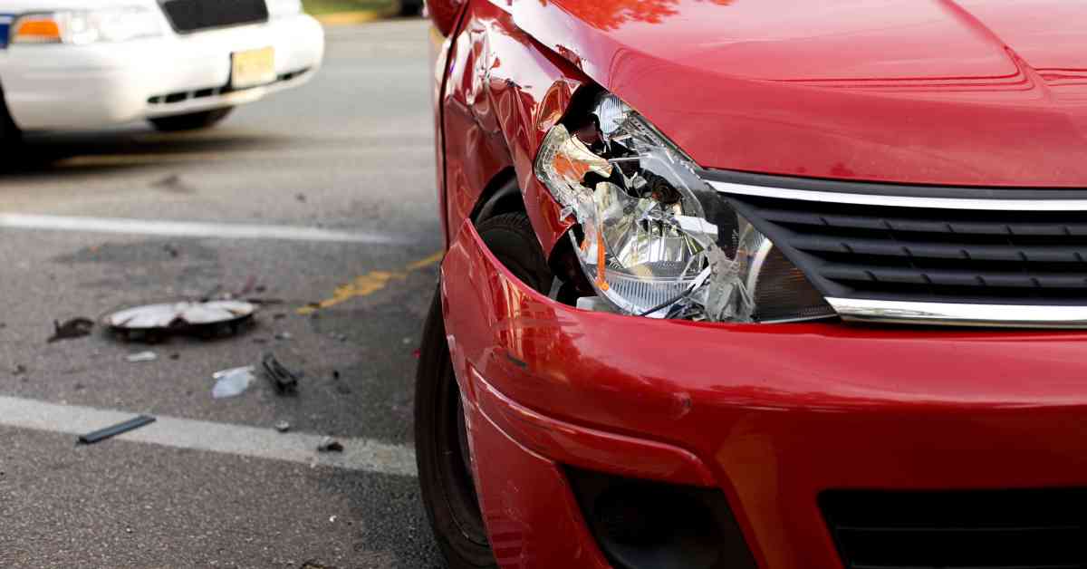 A red car with a damaged headlight after an accident