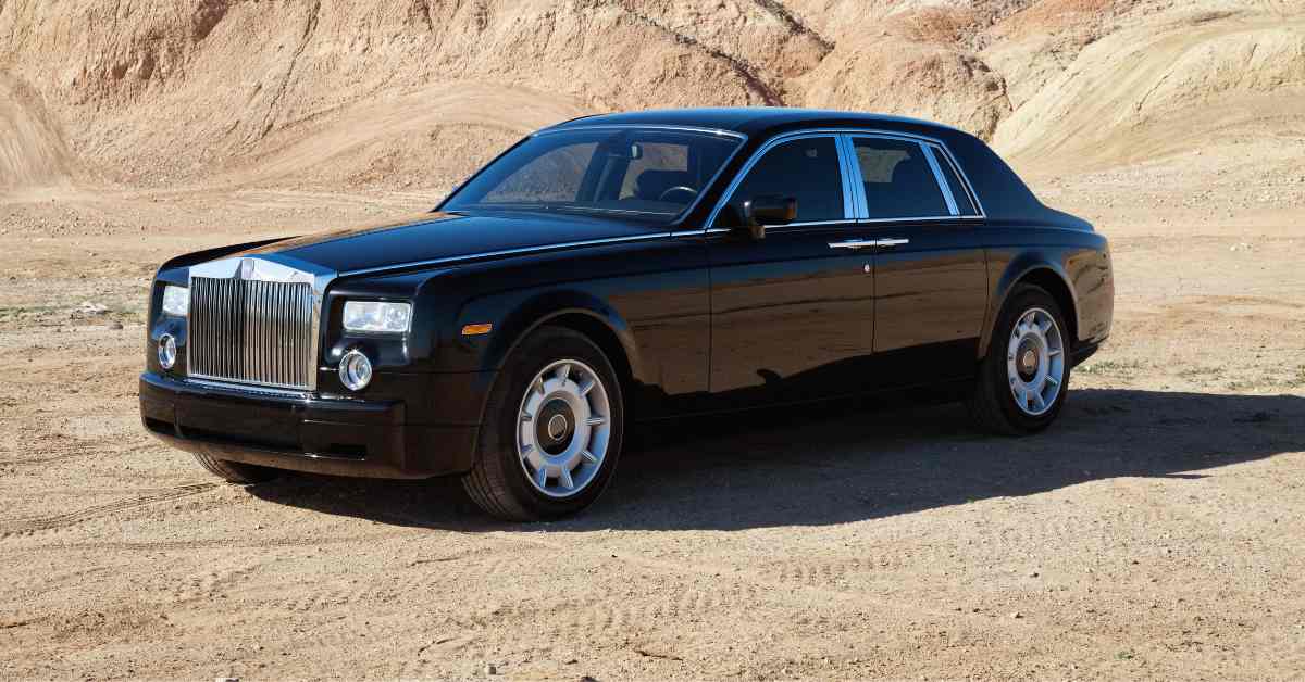 Rolls royce car parked on unpaved road in front of mountains